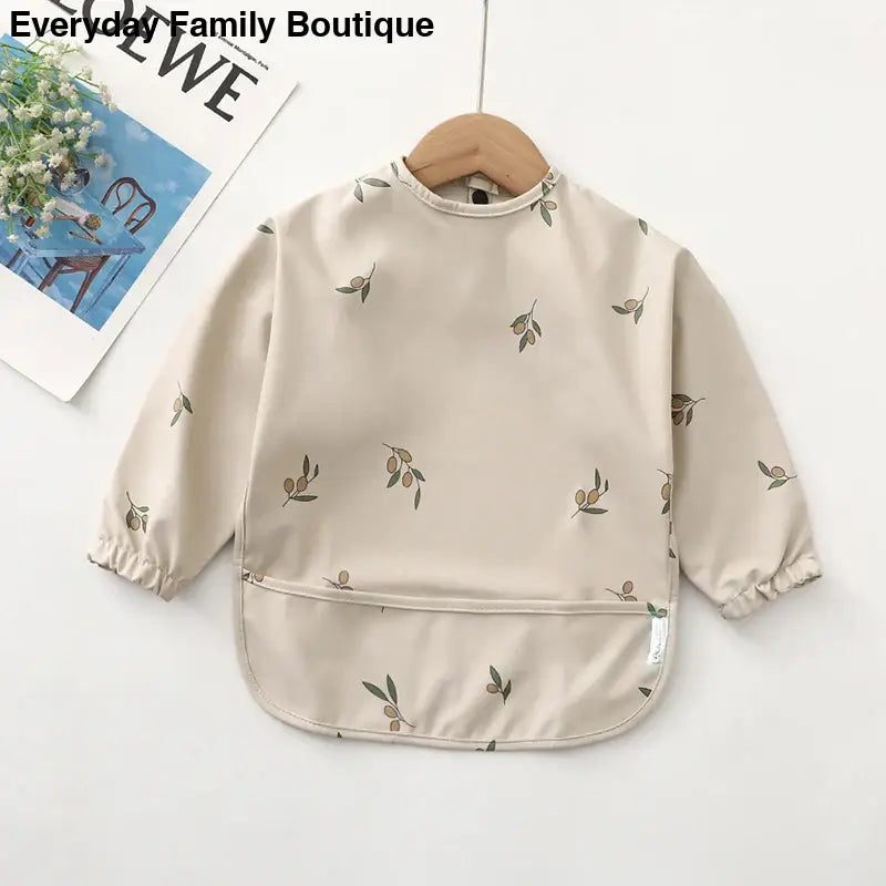 Beige long-sleeved smock with delicate floral print pattern.