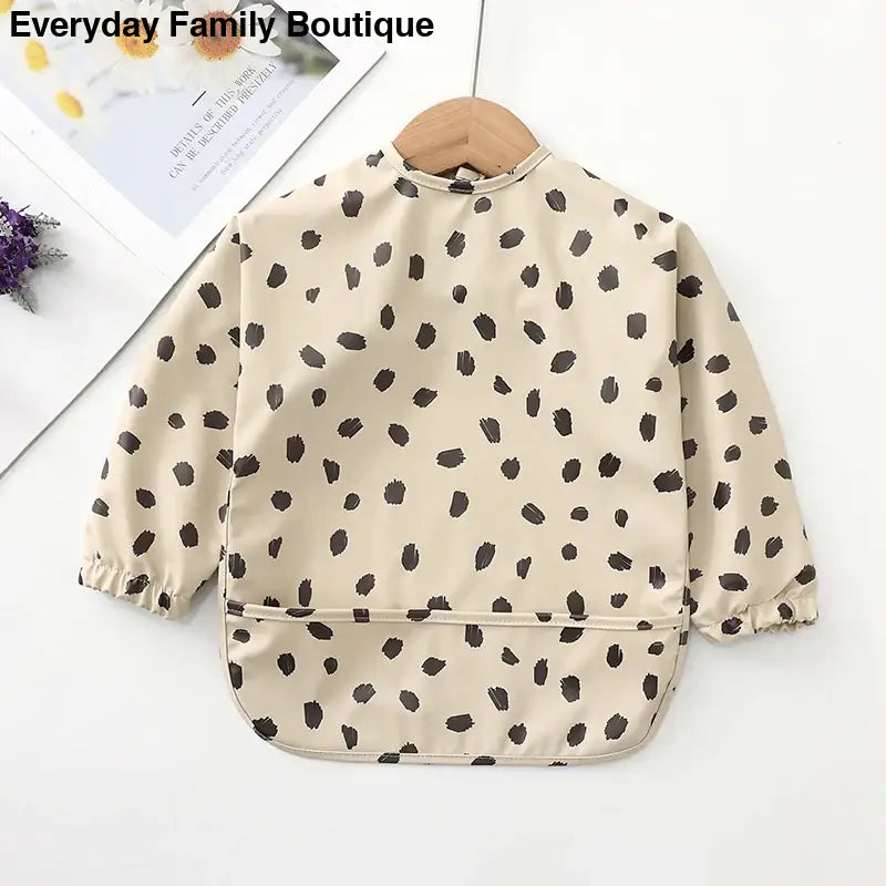 Beige long-sleeved bib with brown polka dot pattern.