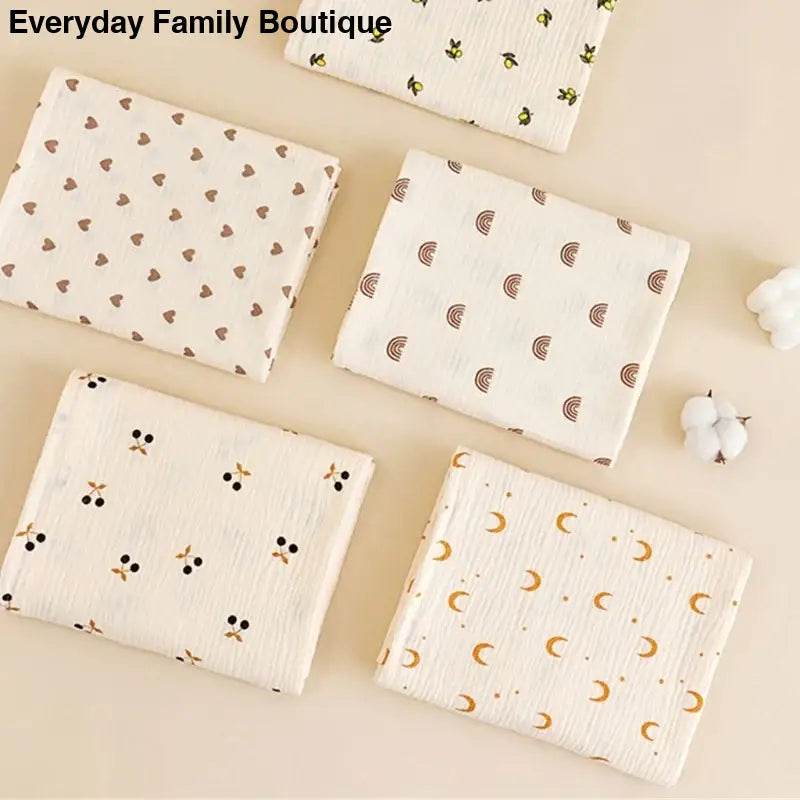 Collection of muslin swaddle blankets with different cute patterns including hearts, rainbows, bees, ghosts, and moons.