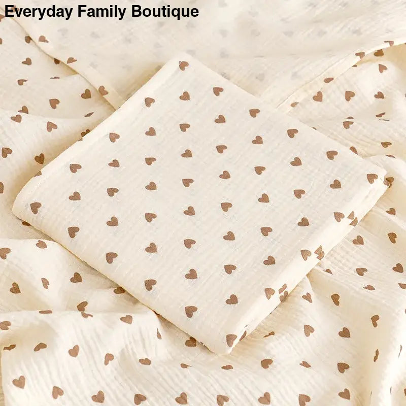 White fabric with a repeating pattern of tiny brown hearts.