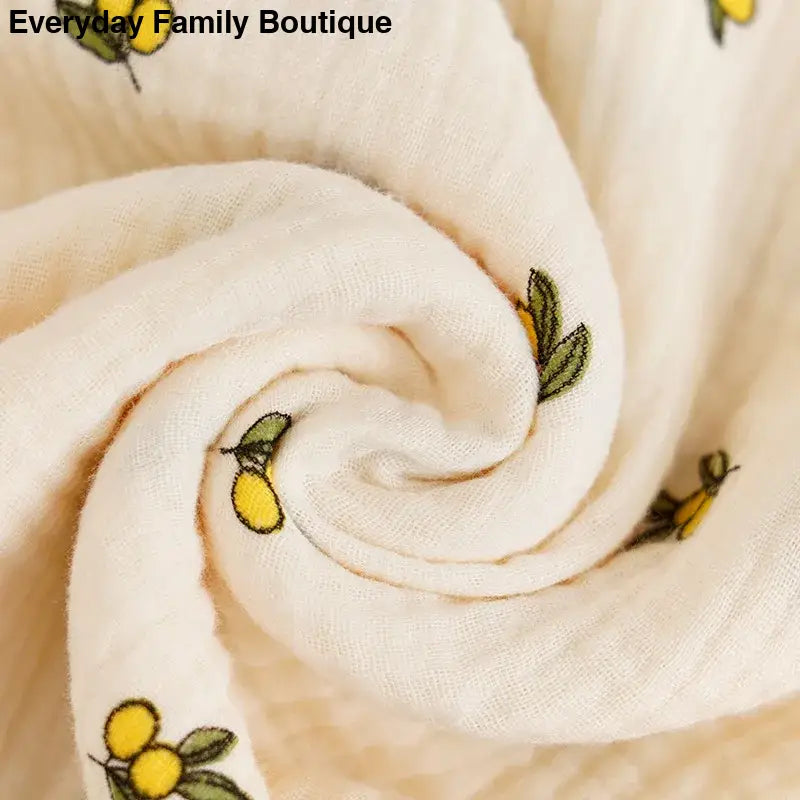 White fabric with a pattern of yellow lemons and green leaves.