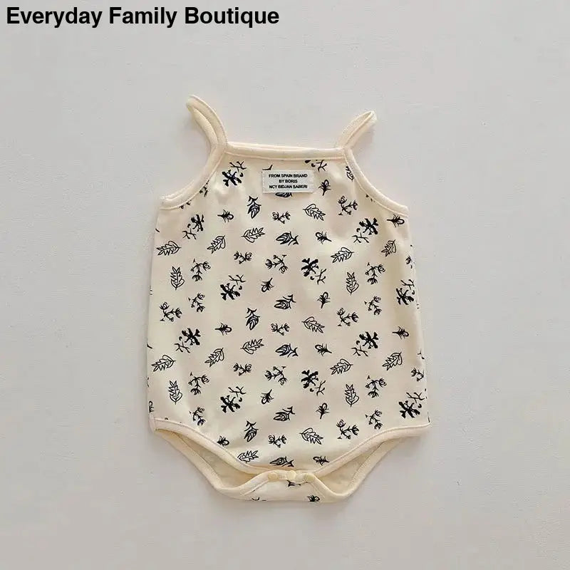 Cream-colored baby bodysuit with tiny black floral print pattern.