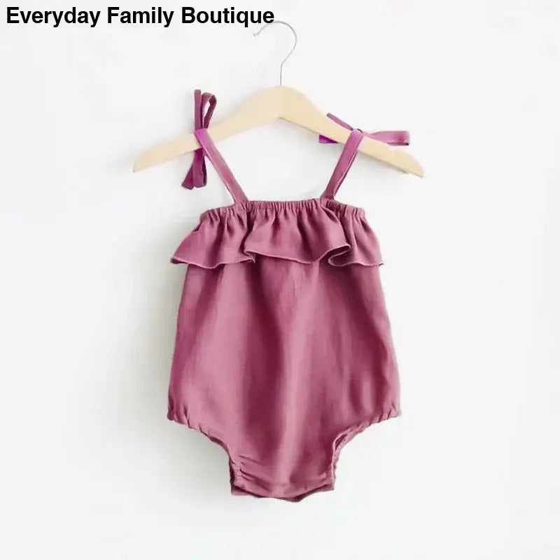 Dusty rose-colored baby romper with ruffled neckline and shoulder ties.