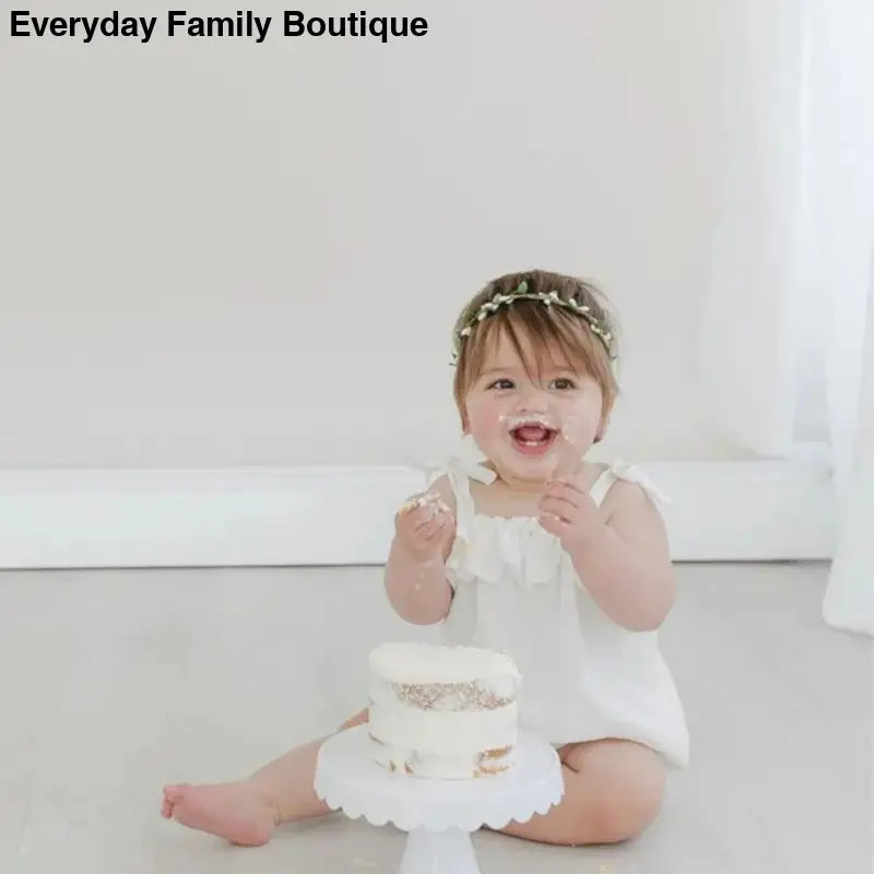 White two-tiered cake on a pedestal stand.