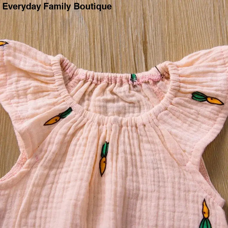 Pink cotton dress with carrot pattern embroidery around the neckline.