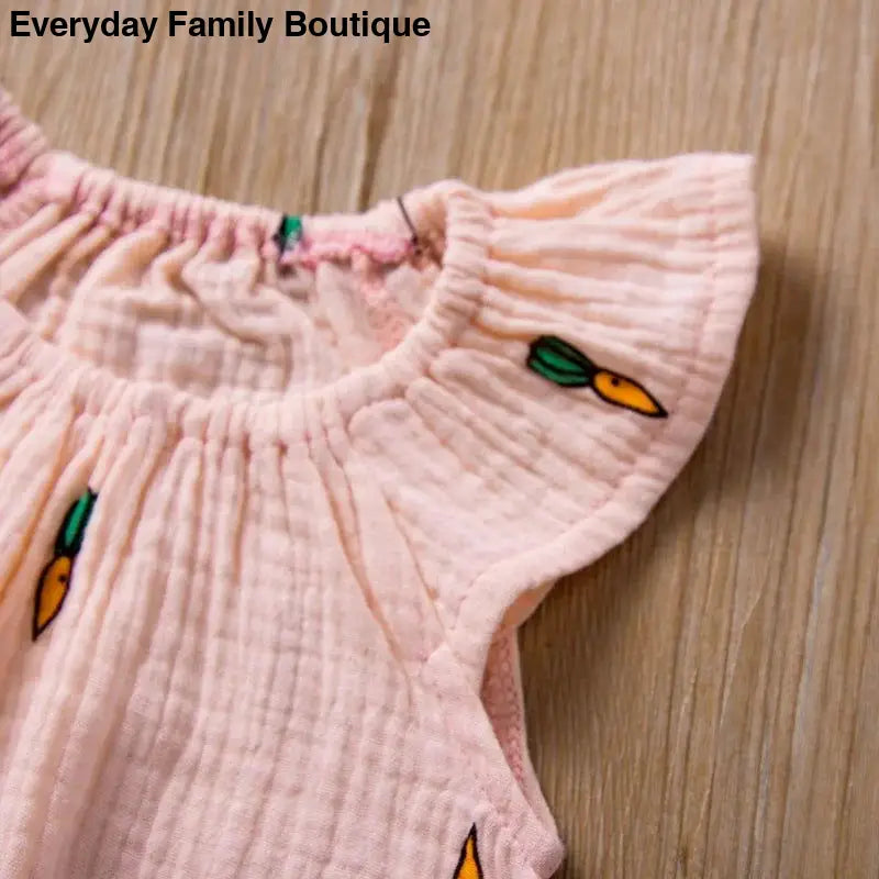 Pink ruffled cotton dress with carrot embroidery details.