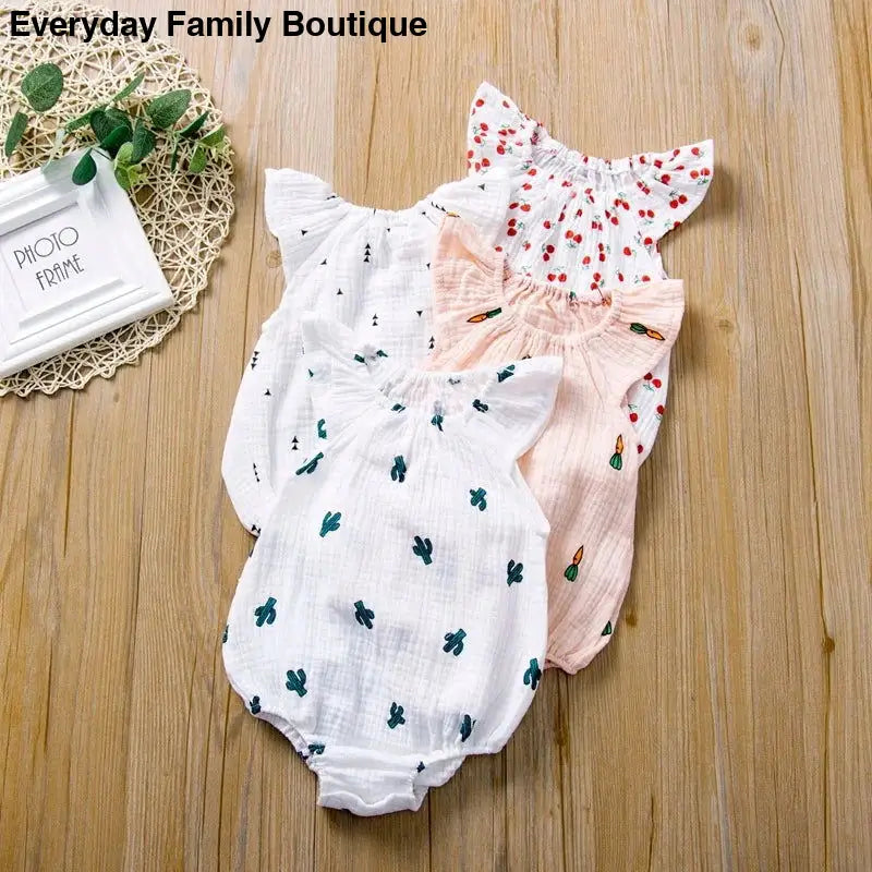 Three delicate baby rompers with ruffled sleeves in white, pink, and floral patterns.