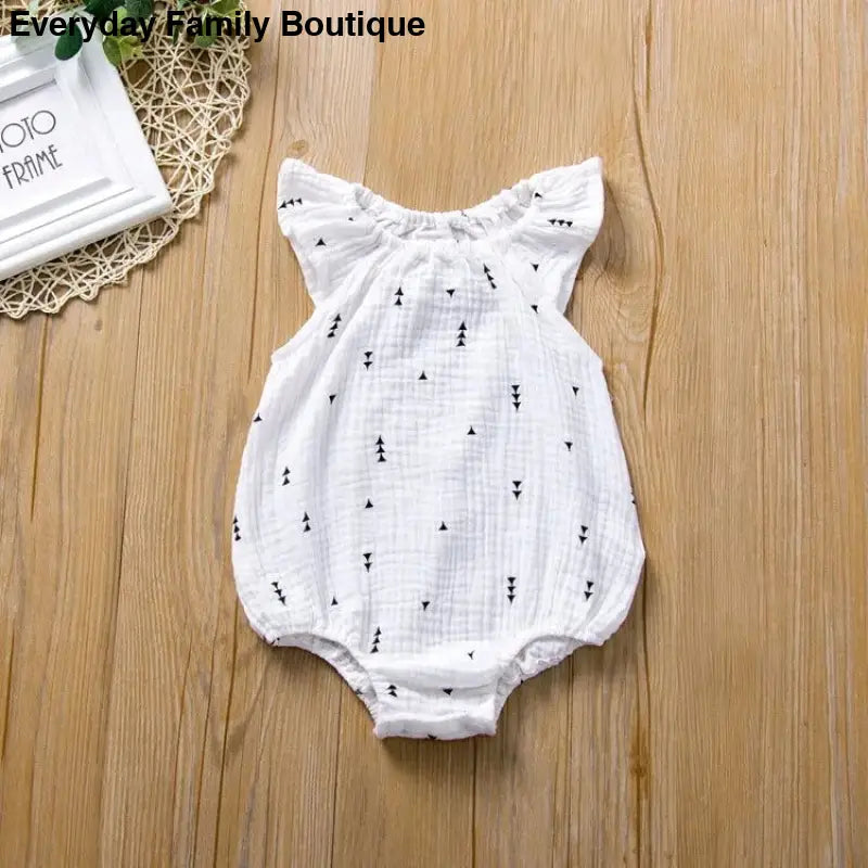 White cotton baby romper with tiny geometric print pattern and ruffled shoulders.