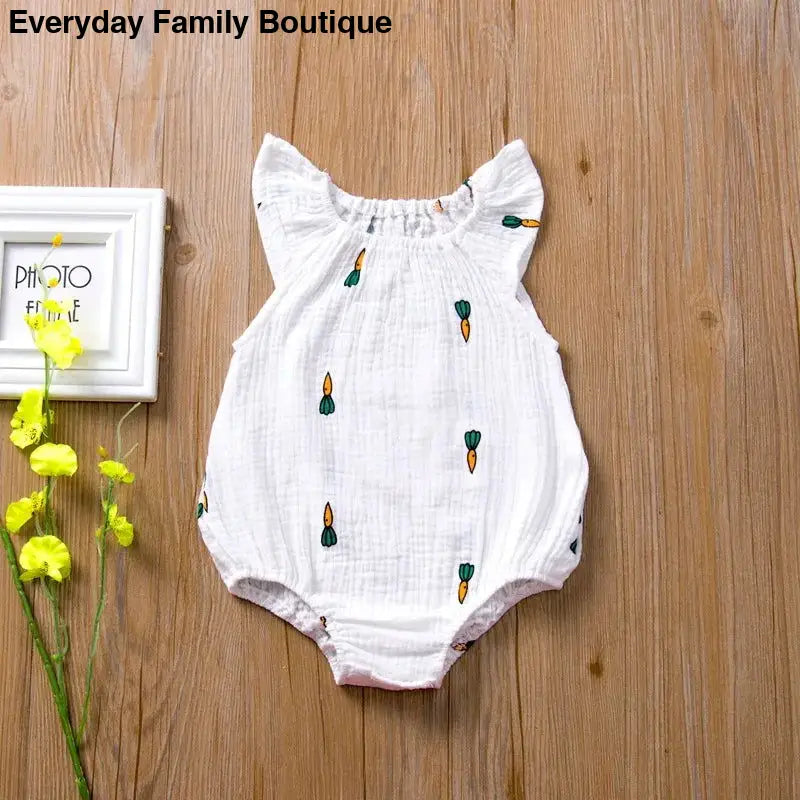 White baby romper with embroidered carrot pattern and ruffled sleeves.