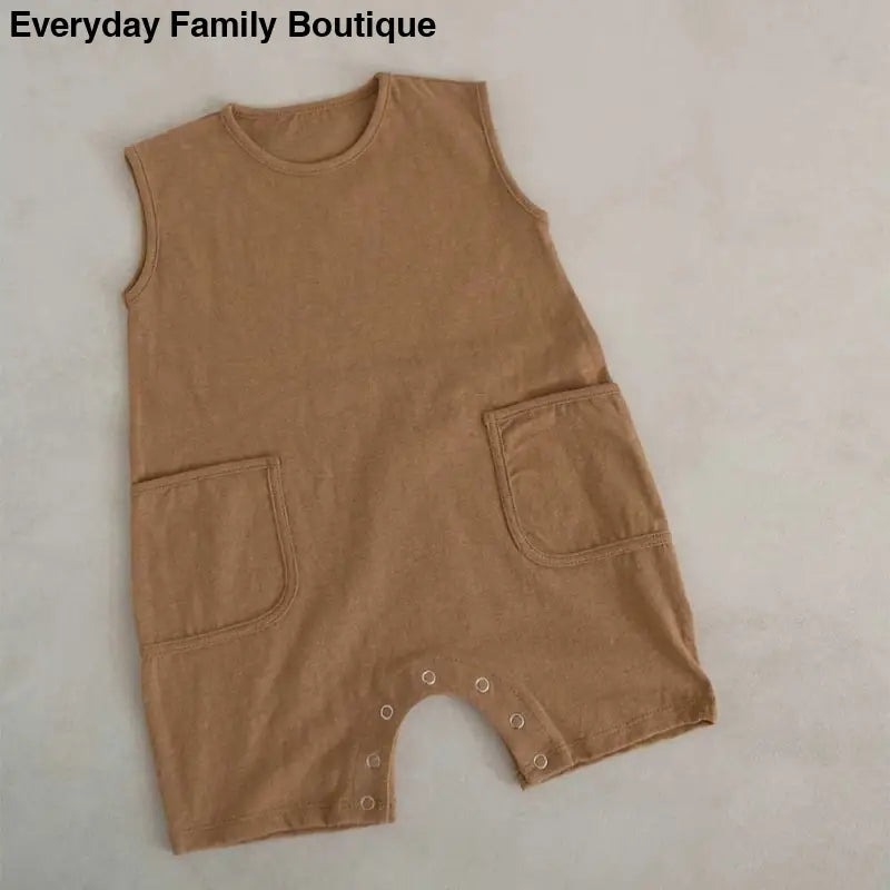 Sleeveless tan cotton romper with front pockets and snap closures at the bottom.