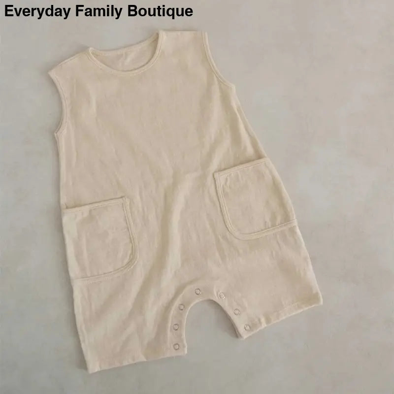 Sleeveless cream-colored baby romper with two front pockets.