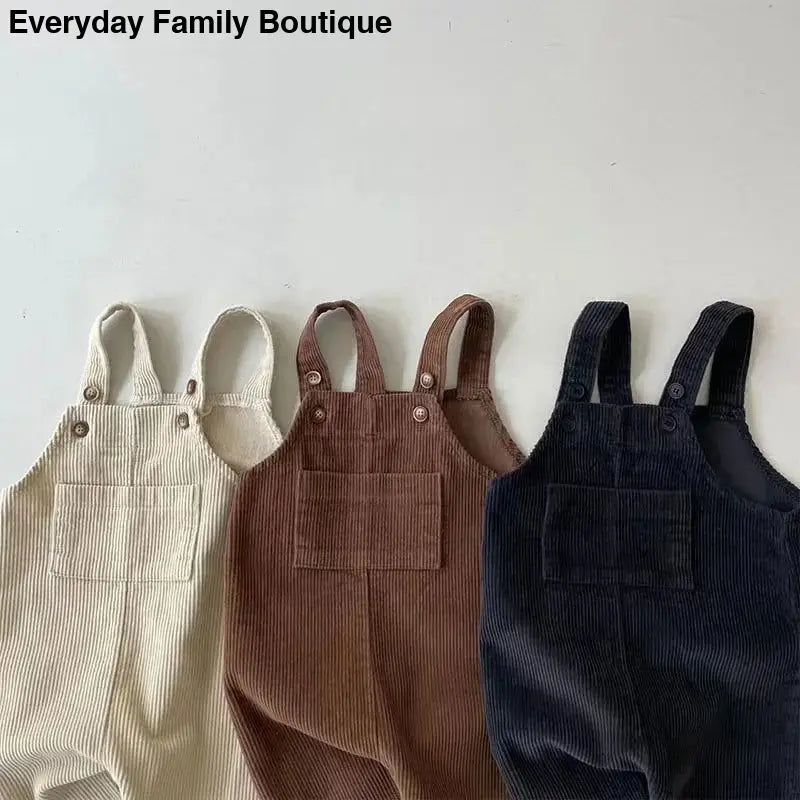 Three corduroy overalls in cream, brown, and navy colors.