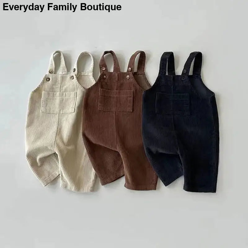 Three pairs of corduroy overalls in beige, brown, and navy blue colors.