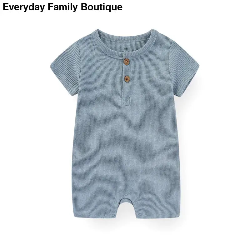 Light blue waffle-knit baby romper with short sleeves and two buttons at the neckline.