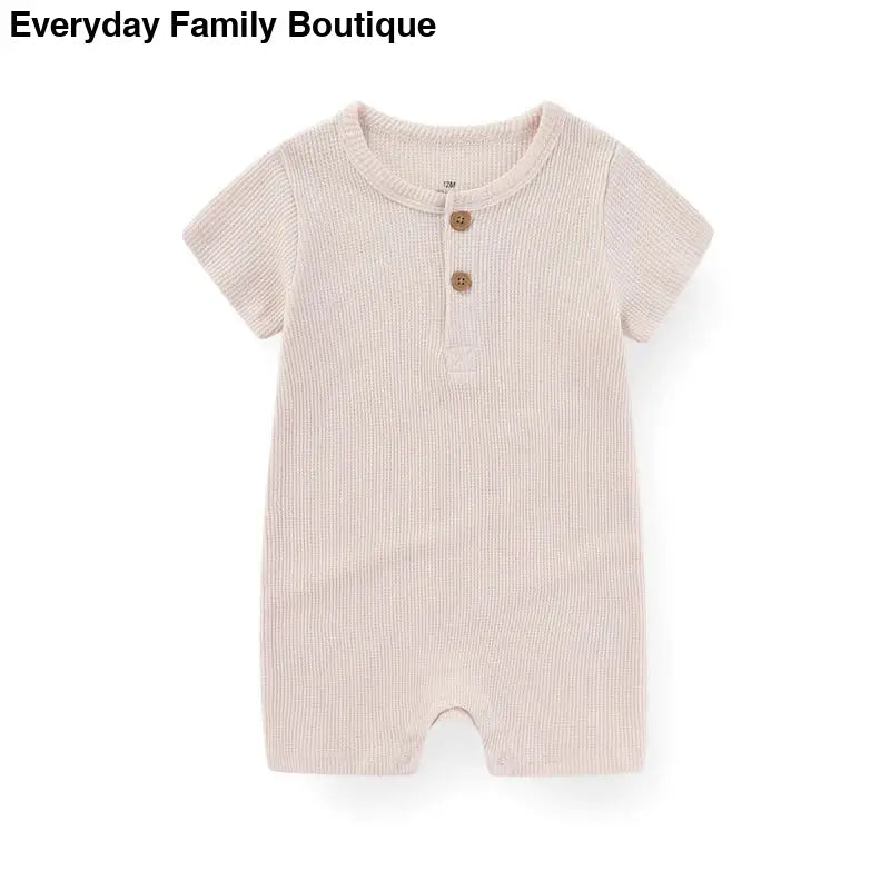 Beige ribbed cotton romper with short sleeves and two wooden buttons at the neckline.