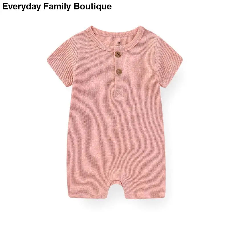 Pink ribbed cotton romper with short sleeves and two buttons at the neckline.