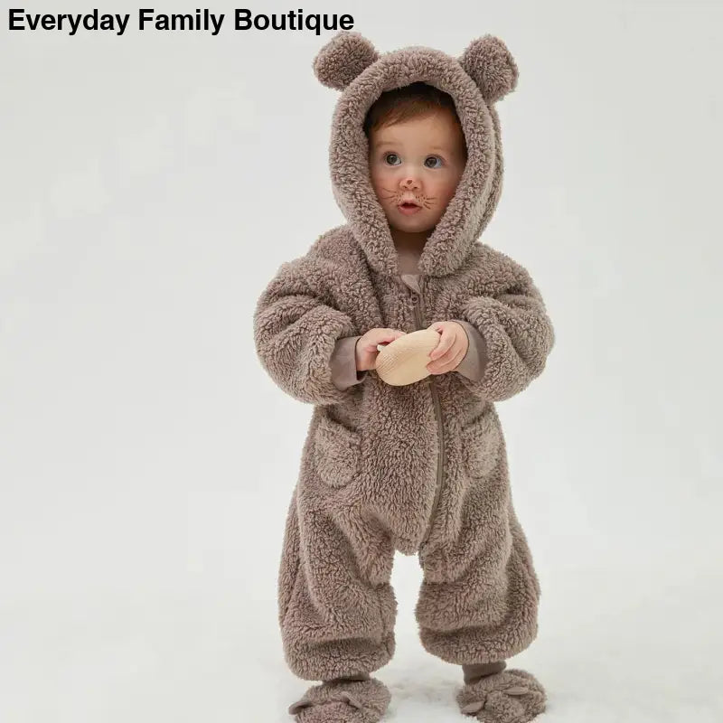 A child wearing a plush teddy bear-style onesie with ears on the hood.