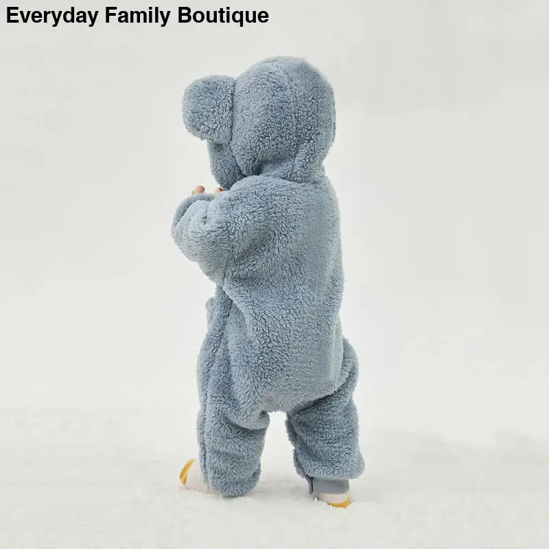 Plush grey teddy bear wearing a hooded onesie and yellow slippers.