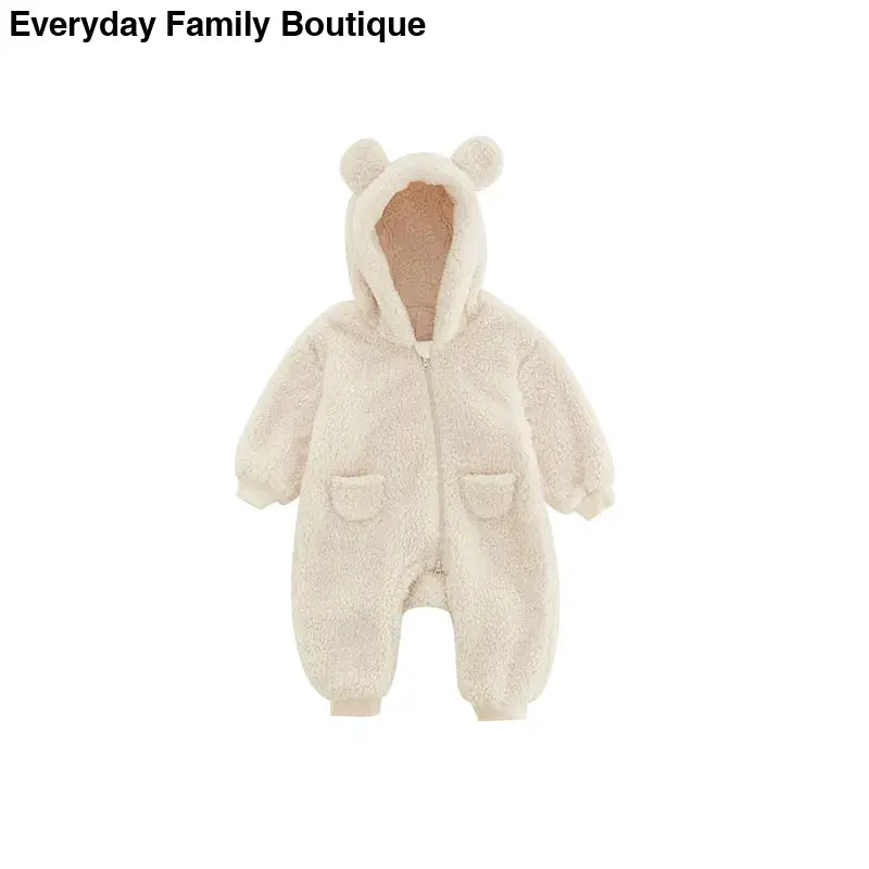 Cream-colored baby onesie with bear ears on the hood and front pockets.