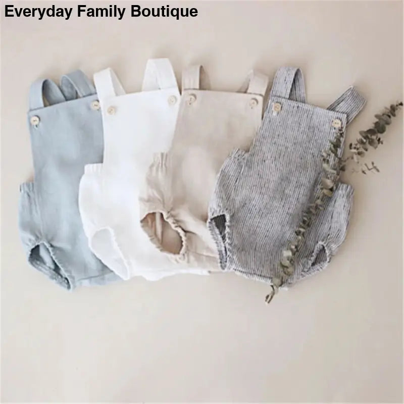 Four baby rompers in soft neutral colors arranged side by side.